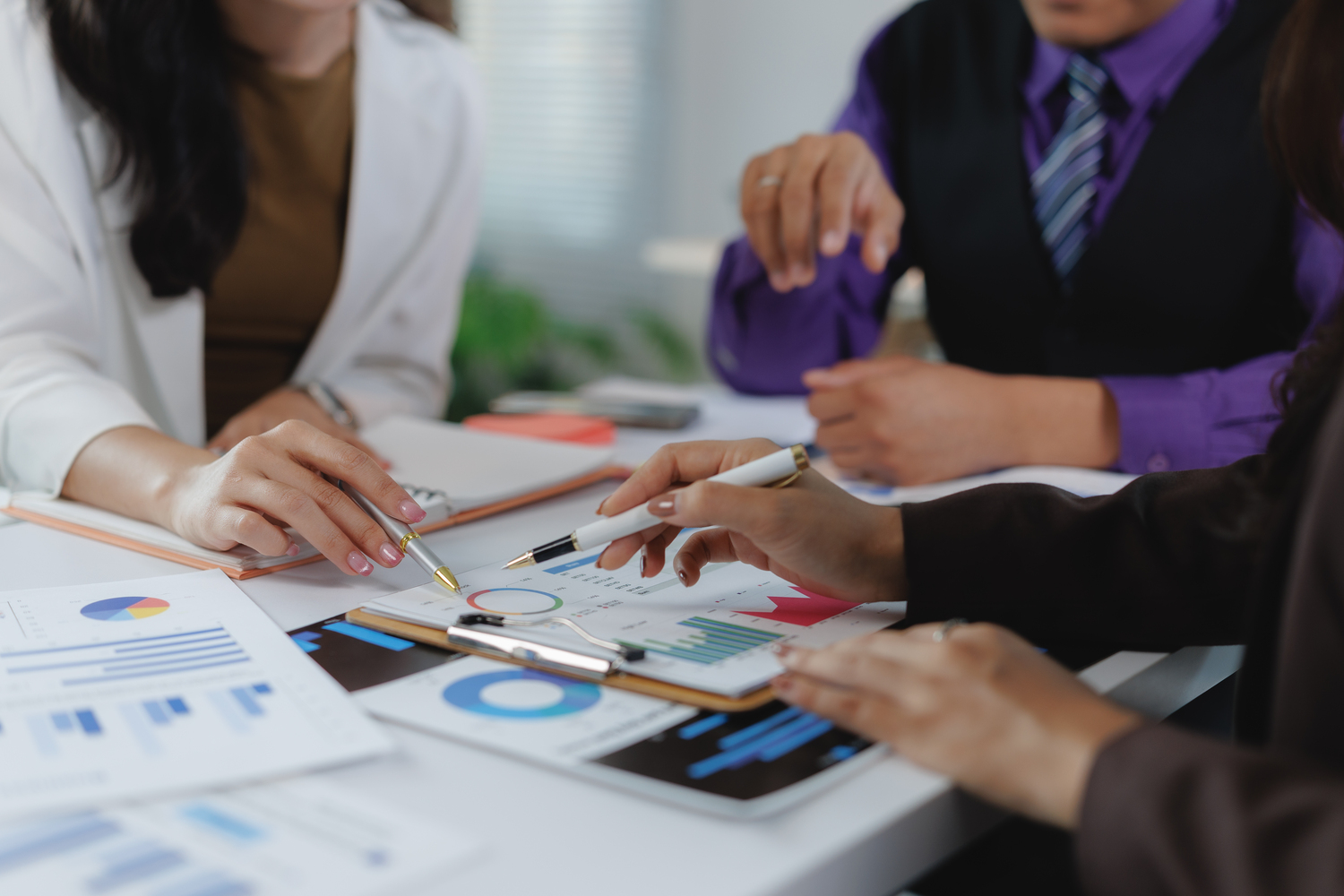 Business people analyzing financial chart discussing project statistics using pen pointing on graph